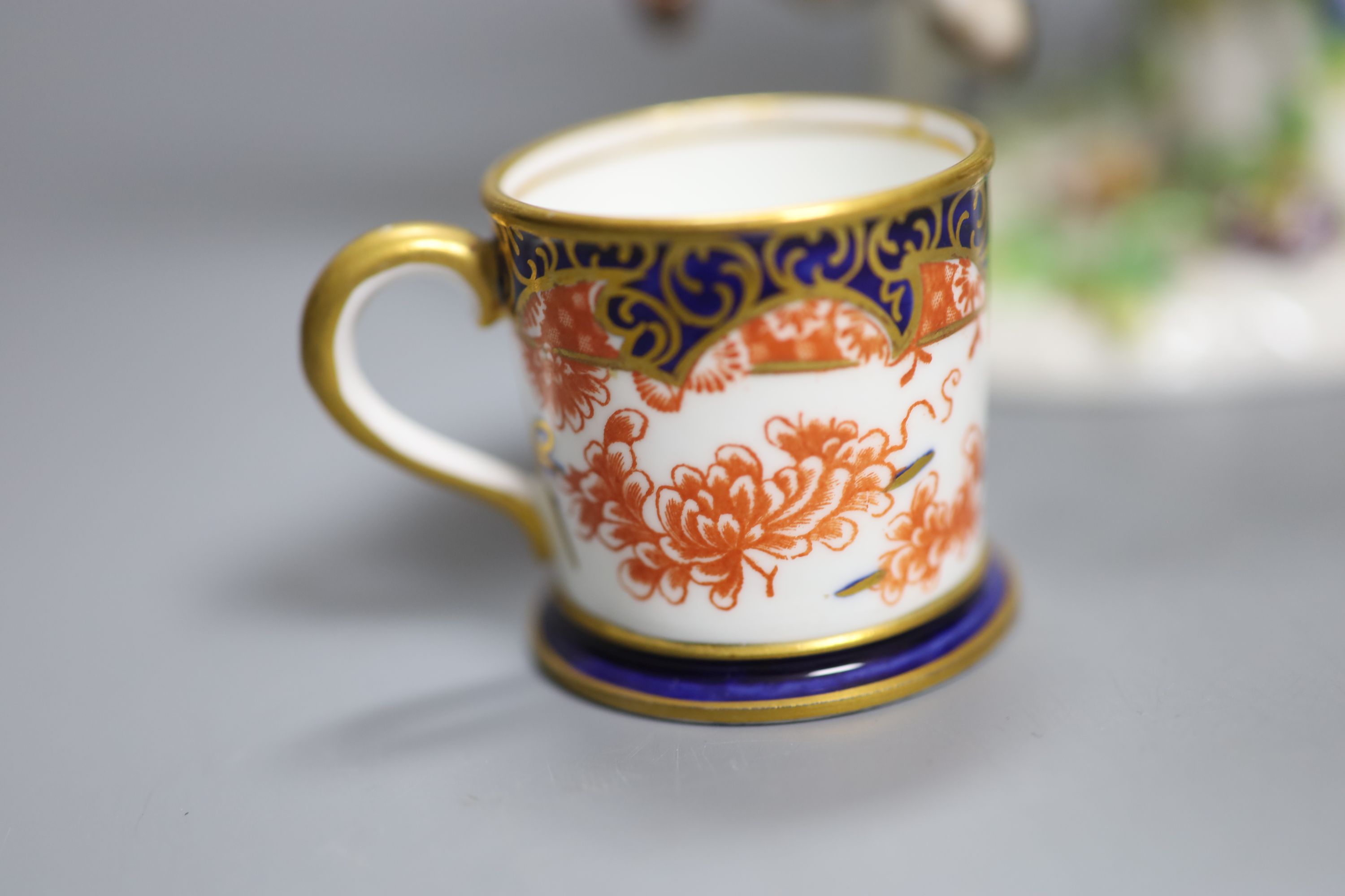 A Continental porcelain figure group, an overlaid glass goblet and a Royal Crown Derby miniature cup, tallest 20cm
